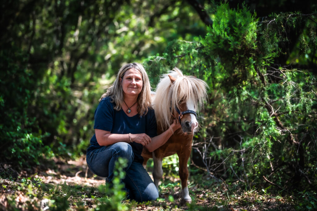 Carole Thomas accroupie avec un de ses poneys